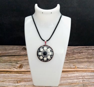 a necklace with a black and white flower pendant