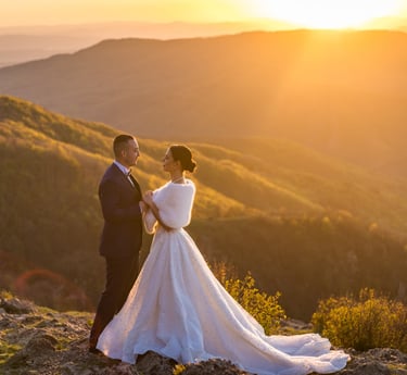 a bride and groom standing on a mountain top