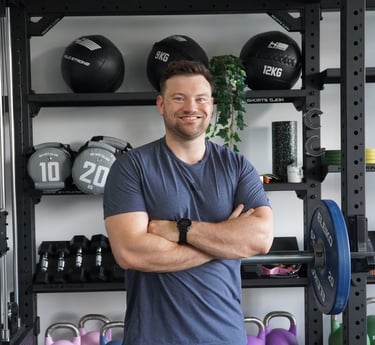 Lächelnder Personal Trainer in Bielefeld posiert im Fitnessstudio mit Kurzhanteln, Kettlebells