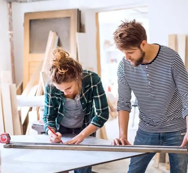 une femme et un homme mesurant une planche de bois