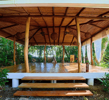 Open-air wooden yoga shala in tropical forest at Rose Temple Grove, designed for feminine embodiment