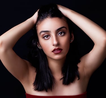 a beautiful brown eyed girl with tanned skin, plump auburn lips, pulling her hair back and posing like a model