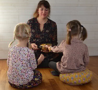 Une femme, Elodie Forget assise en face de deux petites filles pendant un cours de méditation