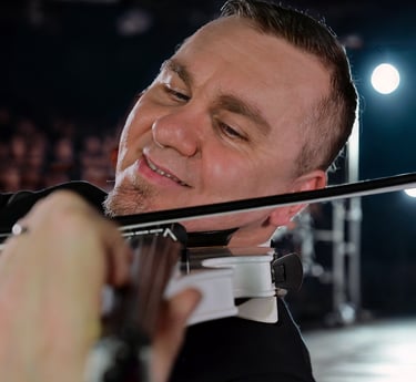 Professional male violinist playing a white electric violin during a live stage performance.