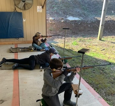 a man and woman are shooting rifles in a shooting range