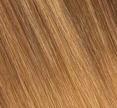Gros plan de rallonges de cheveux lisses et soyeuses dans un balayage mêlant blond miel chaud et bru