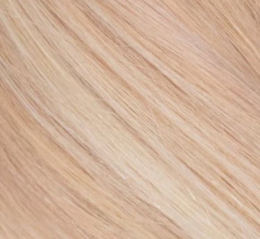Gros plan de la texture de mèches de cheveux soyeuses blond fraise avec des reflets naturels.