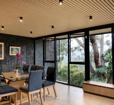 Interior moderno con ventanales de piso a techo y vista al jardín, iluminación cálida