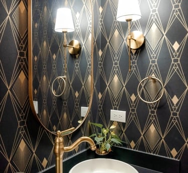 Baño elegante con papel tapiz geométrico, espejo redondo, luminarias doradas y grifería de lujo.