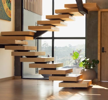 Escalera interior flotante de madera con estructura metálica y fondo acristalado.