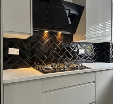 Modern white kitchen featuring a black herringbone tile backsplash and gas stovetop.