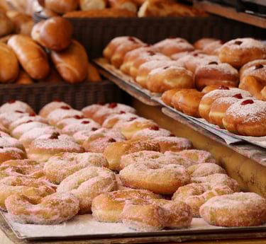 Donuts recién hechos recubiertos de azúcar y rellenos de mermelada expuestos en el mostrador