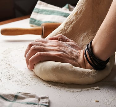 persona amasando una bola de masa con un rodillo al fondo