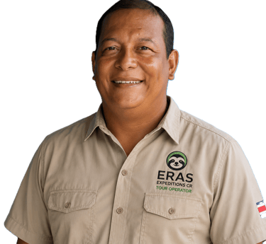 Smiling male tour guide wearing a tan Eras Expeditions CR uniform shirt against a black background.