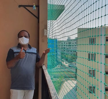 A close-up of a freshly installed white pigeon net covering a balcony in a Bangalore apartment.