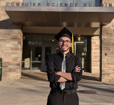 2014, recently graduated Luis posing in front of his Computer Science department.