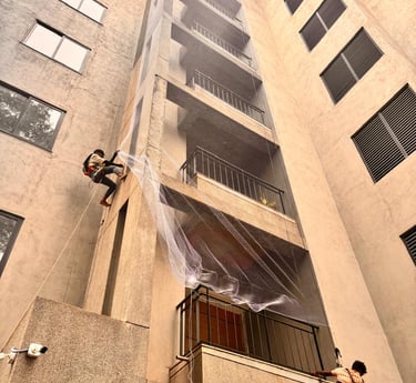 A technician carefully installing a durable pigeon safety net on a sunny apartment balcony overlooki
