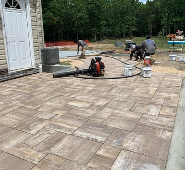 Custom paver patio installation in Port Jefferson Station backyard with outdoor furniture and landsc