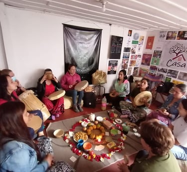 Grupo de mujeres sentadas en círculo durante una ceremonia espiritual con tambores y un altar