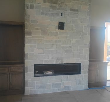 Modern floor-to-ceiling stone fireplace with a linear gas insert and built-in wood cabinets.