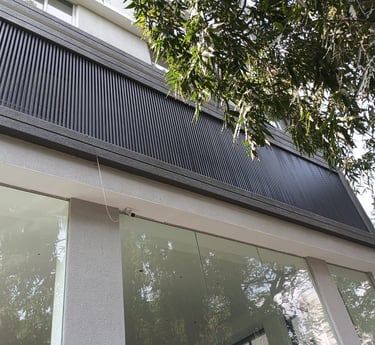 Modern building exterior with glass storefront windows and a decorative dark grey vertical louver panel.
