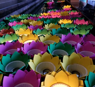 Colorful lotus flower candles floating on water during a Buddhist temple prayer ceremony in Vietnam.