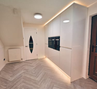 white kitchen with wooden floors and warm cupboard backlighting