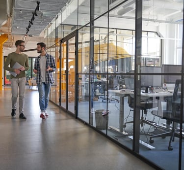 two employees walking down a hallway with a glass wall