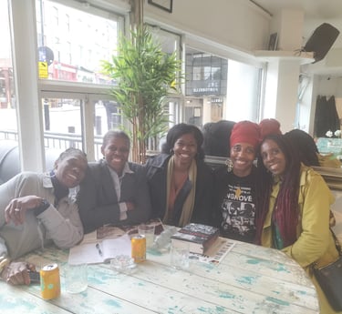 a group of people sitting at a table with drinks discussing Mangrove Nine