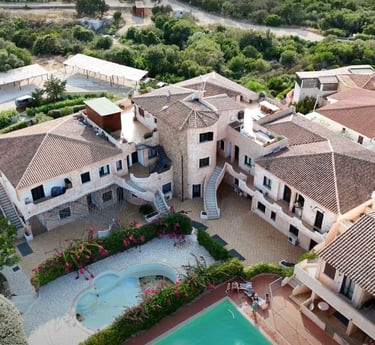 Aerial view of a Mediterranean resort complex with terracotta roofs and luxury swimming pools.