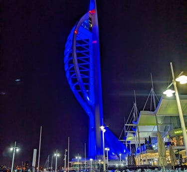 Spinnaker Tower lit up in blue against a dark night sky