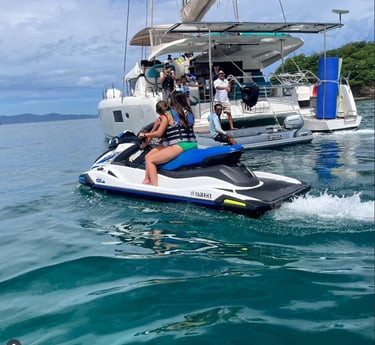 Guests riding jet skis next to Kephas catamaran during private tour in Papagayo Gulf