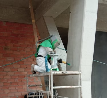 Técnico especialista en el chorreo de arena chorreando hormigón en un andamio
