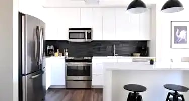 a kitchen with a refrigerator, stove, and stool