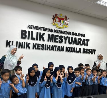 Malaysian preschool students and teachers posing in the Kuala Besut Health Clinic meeting room.