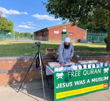 Volunteer setting up a table of free Qurans for distribution in Foleshill, Coventry