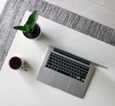 a laptop computer sitting on a table with a cup of coffee and a plant