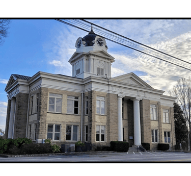 The Franklin County Courthouse in Carnesville, GA with clounds in the sky behind the building.