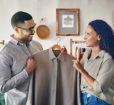a man and woman looking at each other while holding a hanger