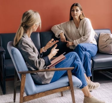 a woman sitting on a couch talking to another woman 