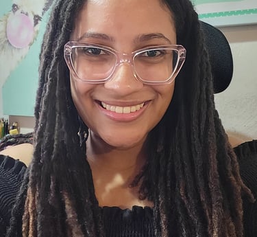 Briele, mulher negra sorrindo com cabelo longo endredado, usando óculos de armação transprente