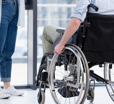 duas pessoas conversando uma mulher em pé e um homem em cadeira de rodas