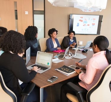 group of African-American women sitting at a conference table and discussing business topics