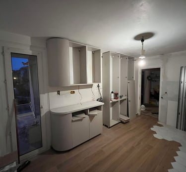 Custom kitchen cabinets being installed in a modern home renovation with wood flooring.