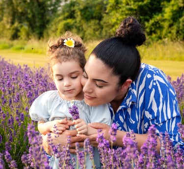 A mother and young daughter bonding in a blooming purple lavender field during golden hour.