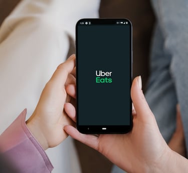 Smartphone affichant le logo Uber Eats, illustrant la possibilité de commander des repas via l'appl 