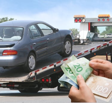 a person holding Canadian dollar bills in front of a junk car on a flatbed