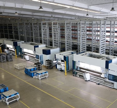 Wide view of an industrial manufacturing facility with metal CNC machinery and high-density storage racks.