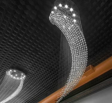 Modern cascading crystal raindrop chandelier lighting hanging from a dark coffered ceiling.