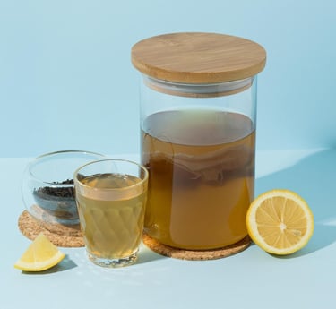 Té de kombucha casero en un frasco de fermentación de vidrio con SCOBY, limón fresco y especias.
